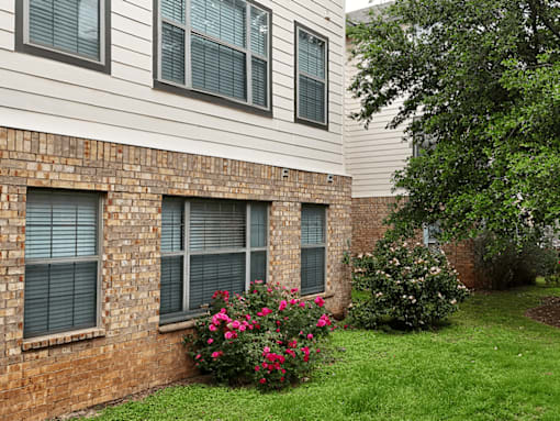 A brick wall with windows and flowers in front.