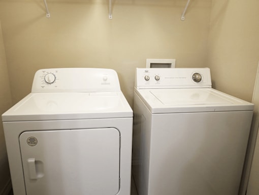 Two white front loading washing machines in a laundry room.