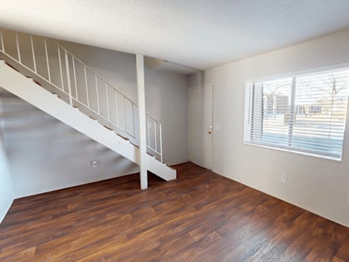 A room with a wooden floor and a staircase.