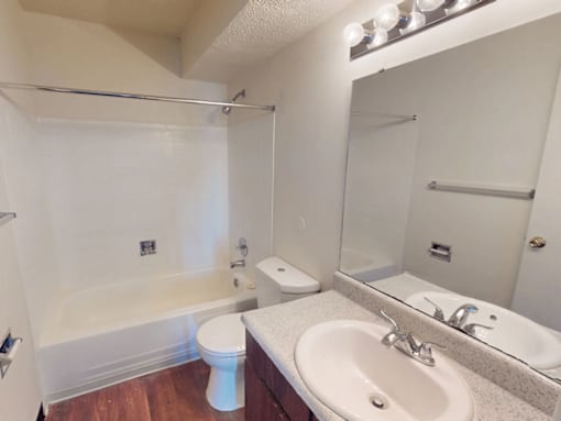 A white toilet sits in a bathroom next to a sink and a bathtub.