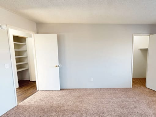 A room with a carpeted floor and two open doors.