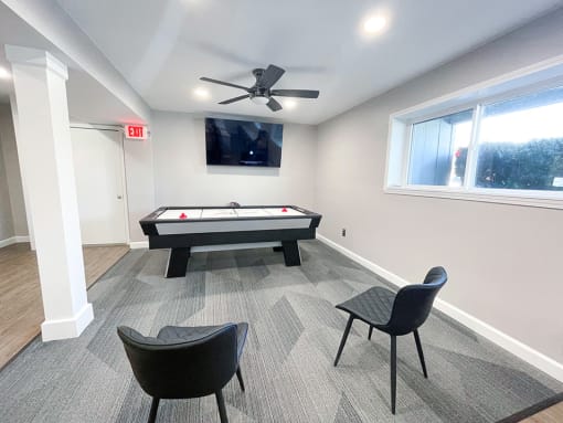 a game room with an air hockey table and a flat screen tv