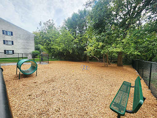A playground with a green slide and two green benches.