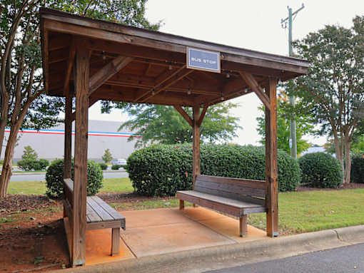 a wooden bench sitting under a wooden pavilion