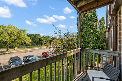 A balcony with a table and chairs overlooks a parking lot.