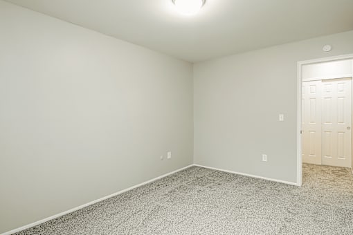 A room with a carpeted floor and a door on the right side.