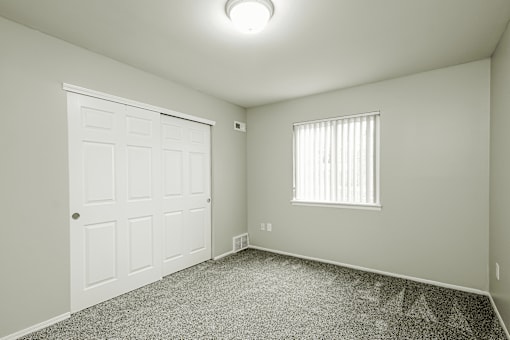 A white door is on the left of a room with a window on the right.
