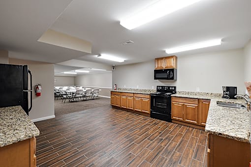 A kitchen with wooden floors and a black refrigerator.