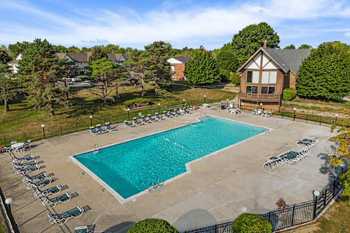 An aerial view of a pool surrounded by chairs and trees.