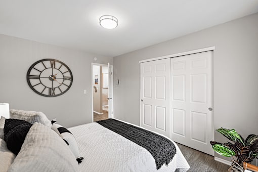 A bedroom with a bed, a clock, and a door.