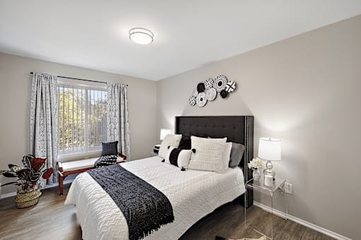 A bedroom with a large bed and a window with curtains.