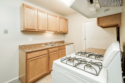 A white gas stove is in a kitchen with wooden cabinets.