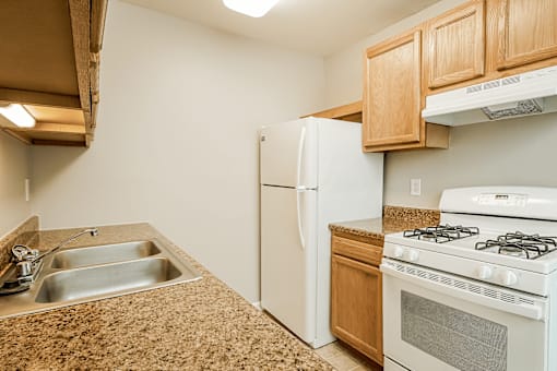 A kitchen with a white refrigerator, stove, and sink.