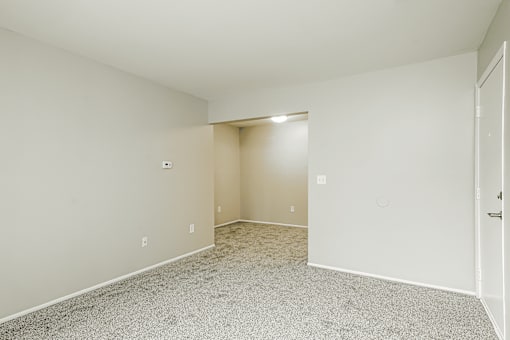 A large empty room with a carpeted floor and white walls.