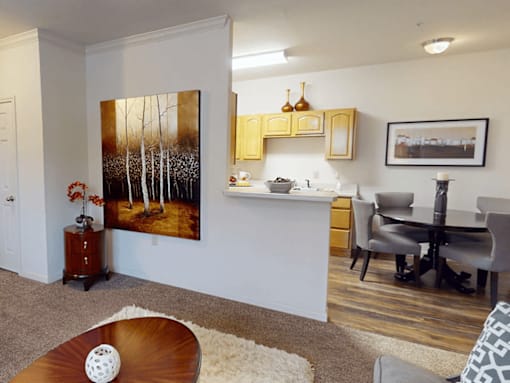 A living room with a painting of trees on the wall.