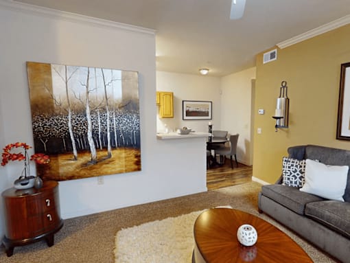 A living room with a painting of birch trees on the wall.