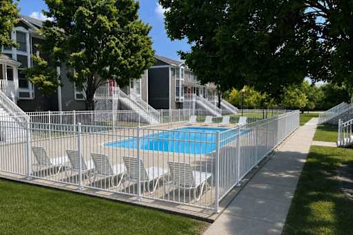 A pool surrounded by a metal fence with chairs on it.