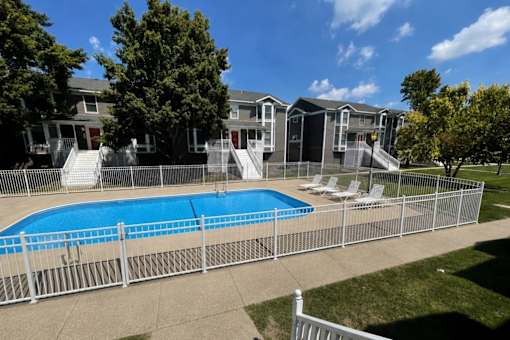 A pool surrounded by a fence with a building in the background.