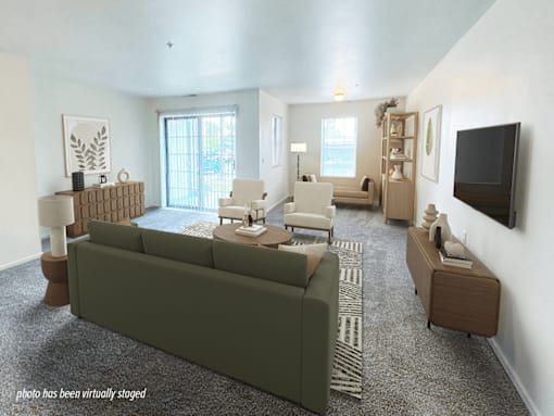 A living room with a green couch and a television on the wall.