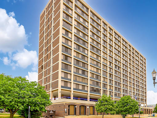 A tall building with many windows and a tree in front of it.