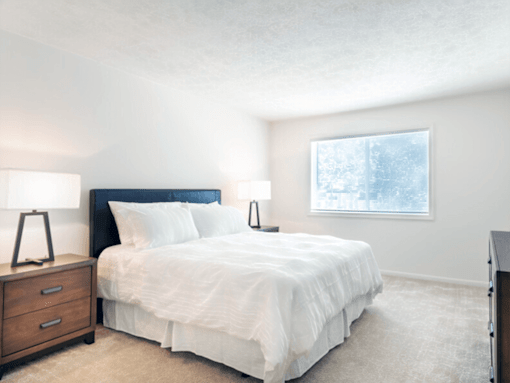 A bedroom with a bed, nightstands, and a window.