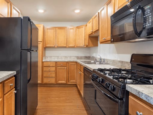 A kitchen with black appliances and wooden cabinets.