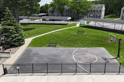 A basketball court is surrounded by a black fence.