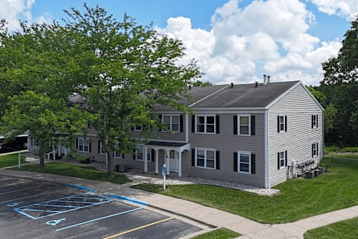 A grey building with a parking lot in front of it.