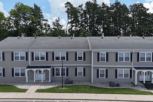 A grey apartment building with a green lawn in front.