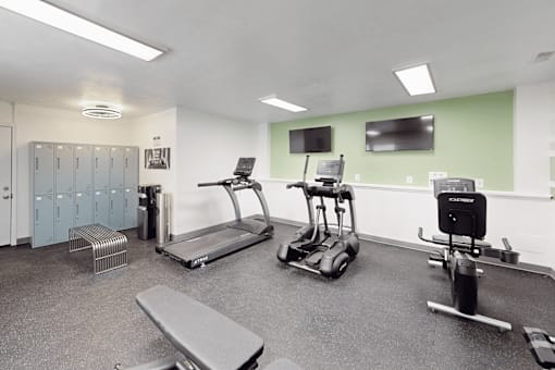 A gym with treadmills, elliptical machines, and a bench.