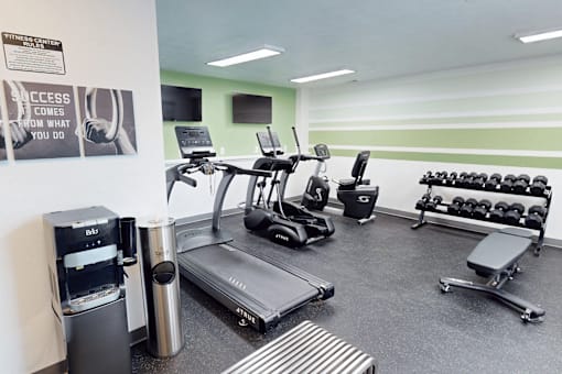 A gym with equipment, weights, and televisions.