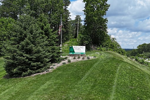 A green sign with white text on a grassy hill.