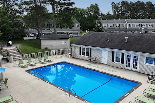 A swimming pool surrounded by lounge chairs and a building in the background.
