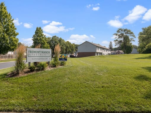 a sign in the grass in front of a building
