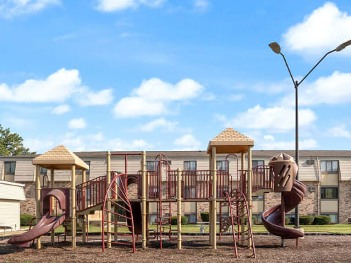 a playground with a set of slides in front of apartment building