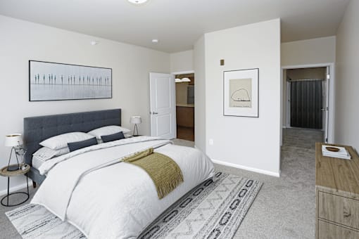 A bedroom with a large bed and a rug on the floor.
