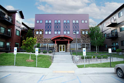 A building with a red door and a stone wall in front.