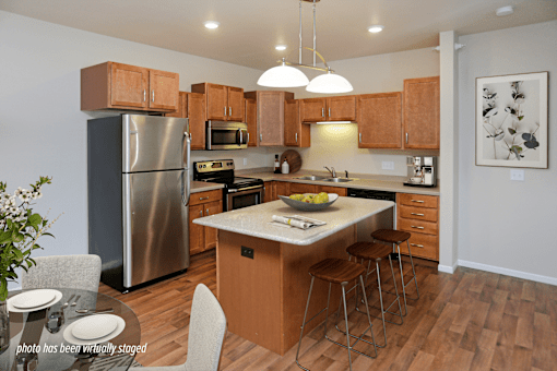 A kitchen with wooden cabinets and a stainless steel refrigerator.