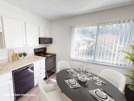 A black table is set for a meal in a white kitchen.