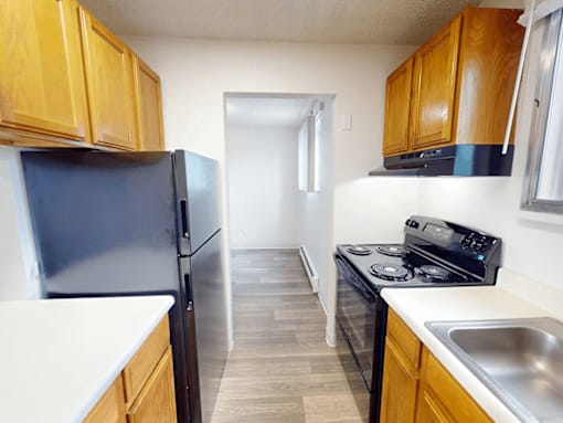A kitchen with a black fridge and stove top oven.