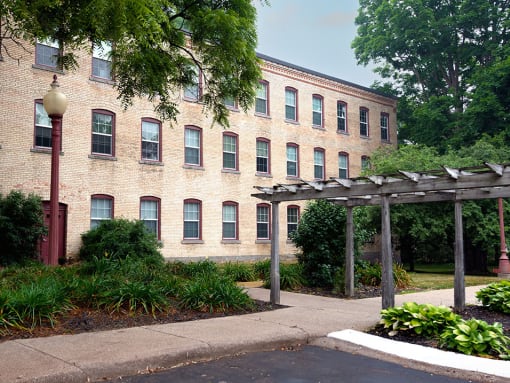a brick apartment building with a wooden pergola