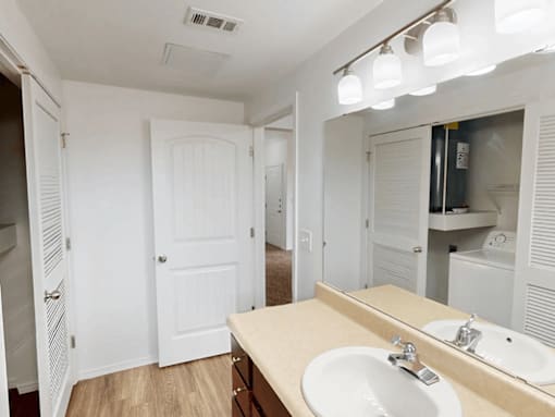A bathroom with a sink, mirror, and lighting fixture.
