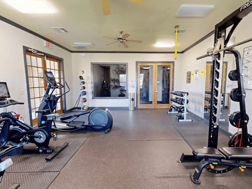A gym with exercise equipment and a fan.