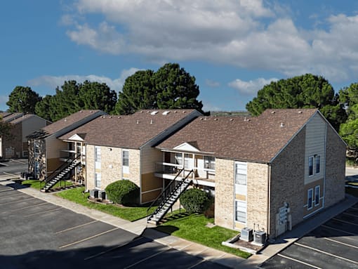 Apartment complex with a parking lot in front.