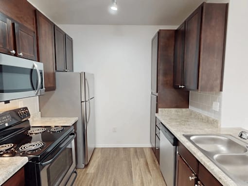 A kitchen with a stove, refrigerator, and microwave.