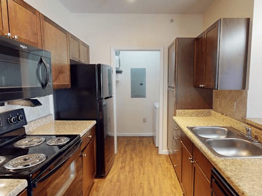 A kitchen with black appliances and wooden cabinets.