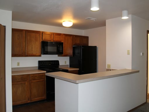 apartment kitchen with a black stove top oven next to a black refrigerator