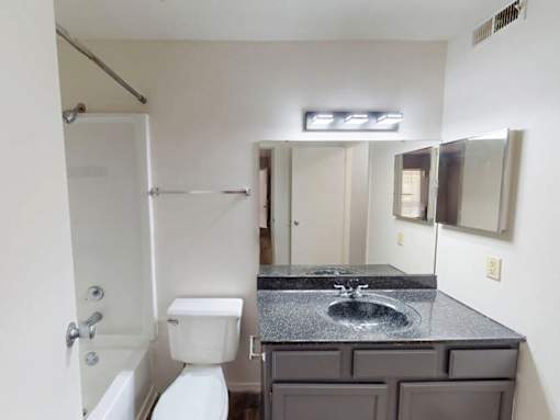 A bathroom with a white toilet, sink, and mirror.