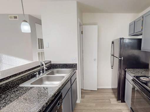 A kitchen with black granite countertops and a black refrigerator.
