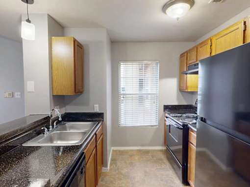 A kitchen with a black granite countertop and wooden cabinets.